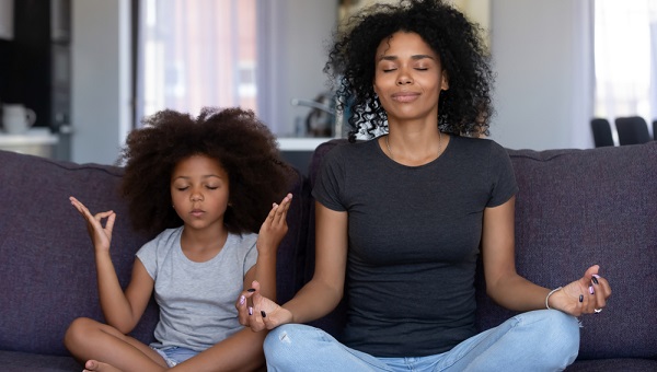 woman and her daughter meditating on a purple couch