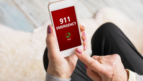 woman holding phone dialing the emergency number