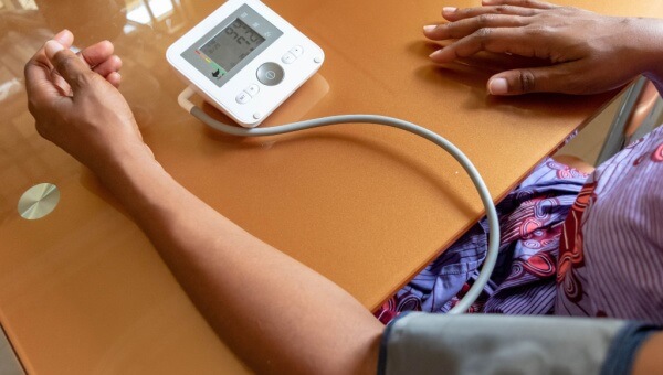 woman wearing blood pressure cuff and reading the results
