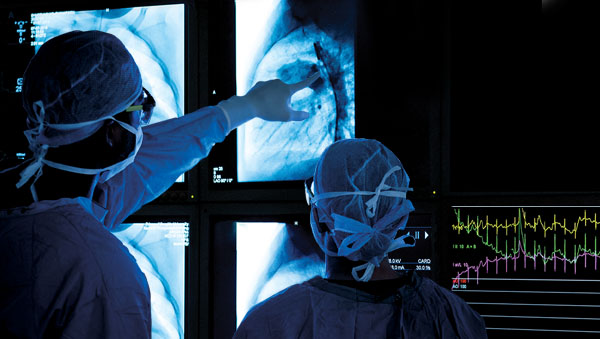 Two surgeons looking at a medical scan in a dark operating room.