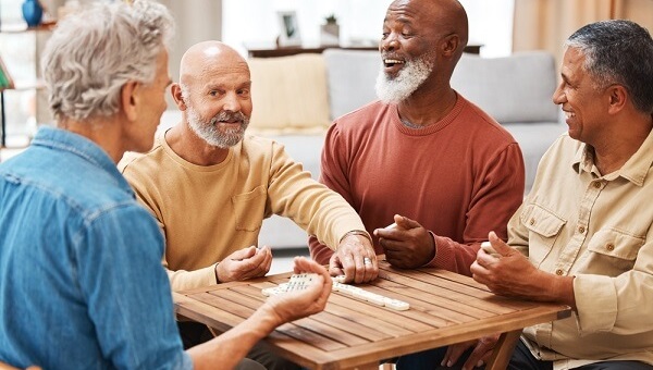 group of older men sitting around table laughing