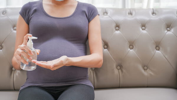 Avoiding Infection In Pregnancy pregnant woman sitting on couch with dispenser