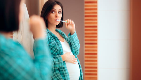 Brushing for Two pregnant woman looking in mirror while brushing teeth